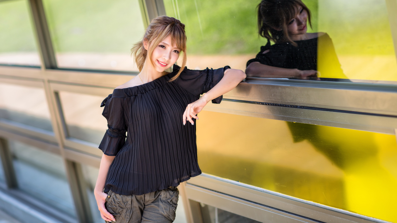 Девушка азиатка в черной блузке у окна