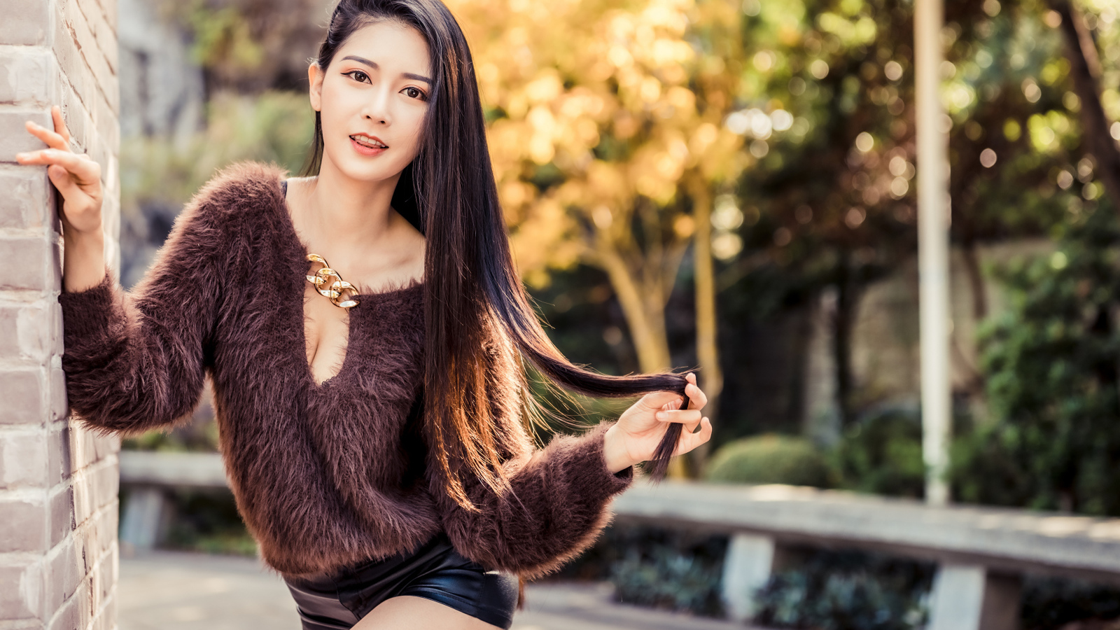 Девушка азиатка в черных шортах у стены