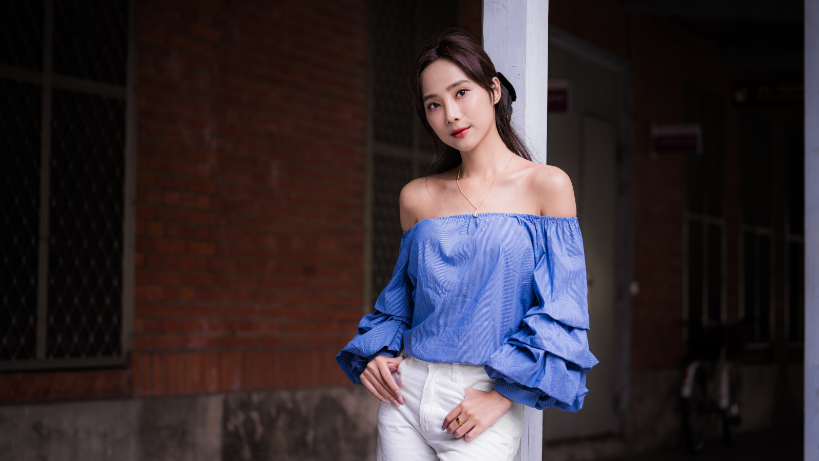 Девушка азиатка в белых брюках у дома