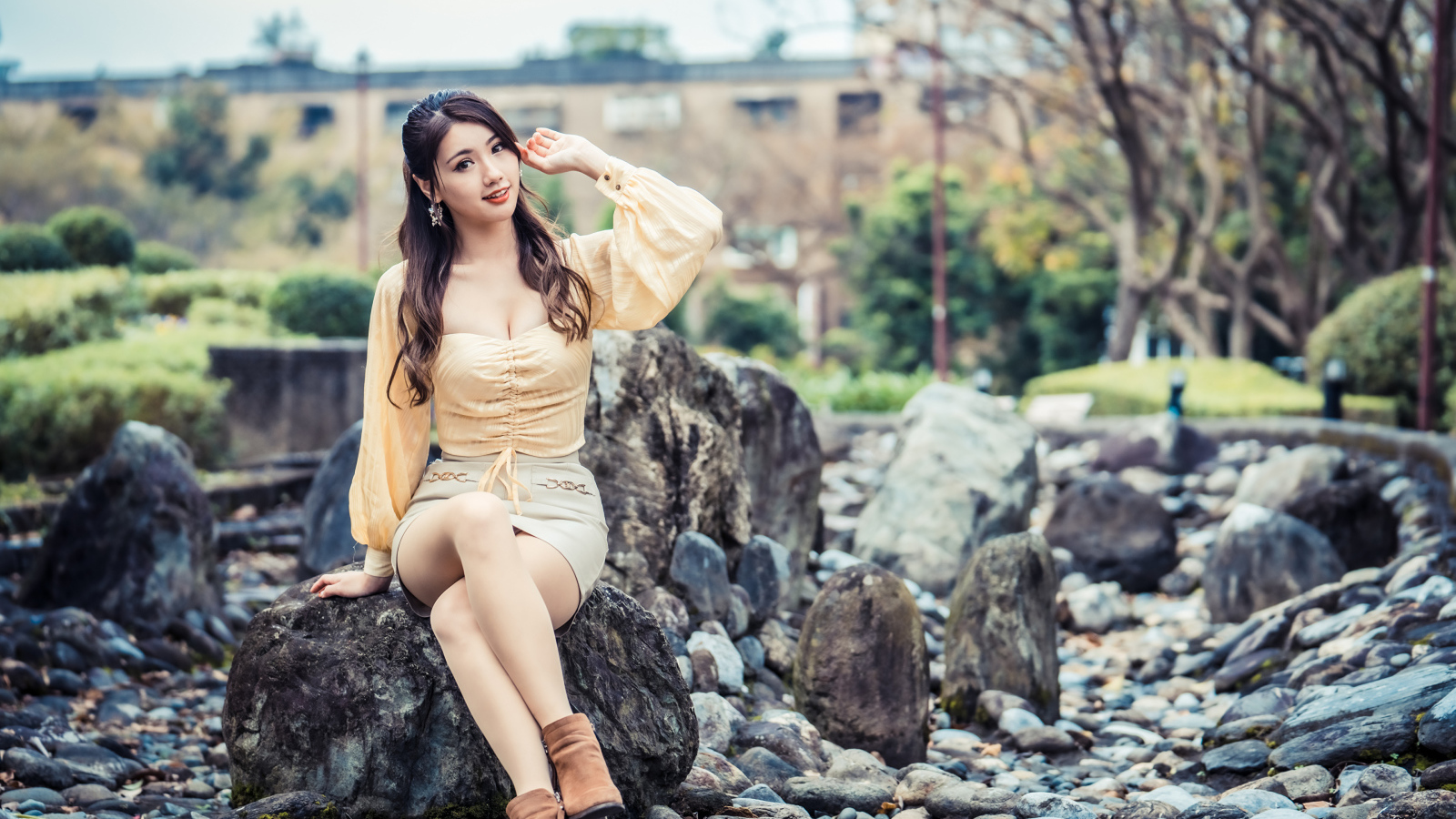 Красивая девушка азиатка сидит на камне