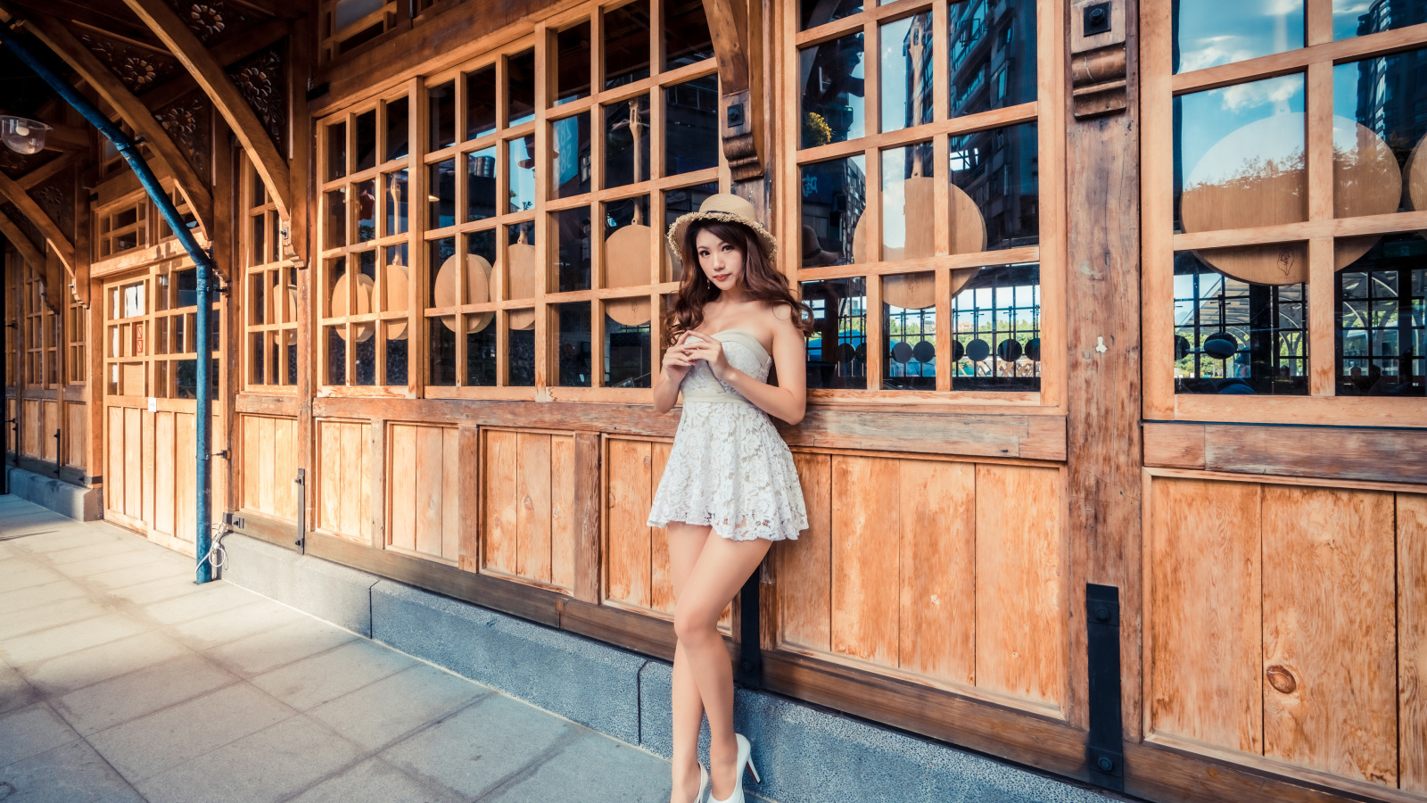 Красивая девушка азиатка стоит у стены с большими окнами