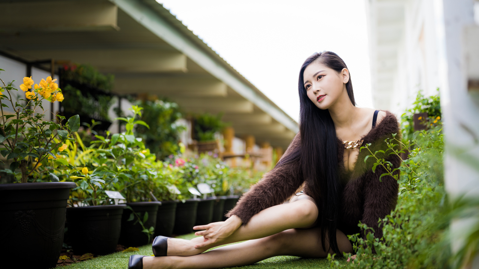 Красивая азиатка сидит на земле у цветов