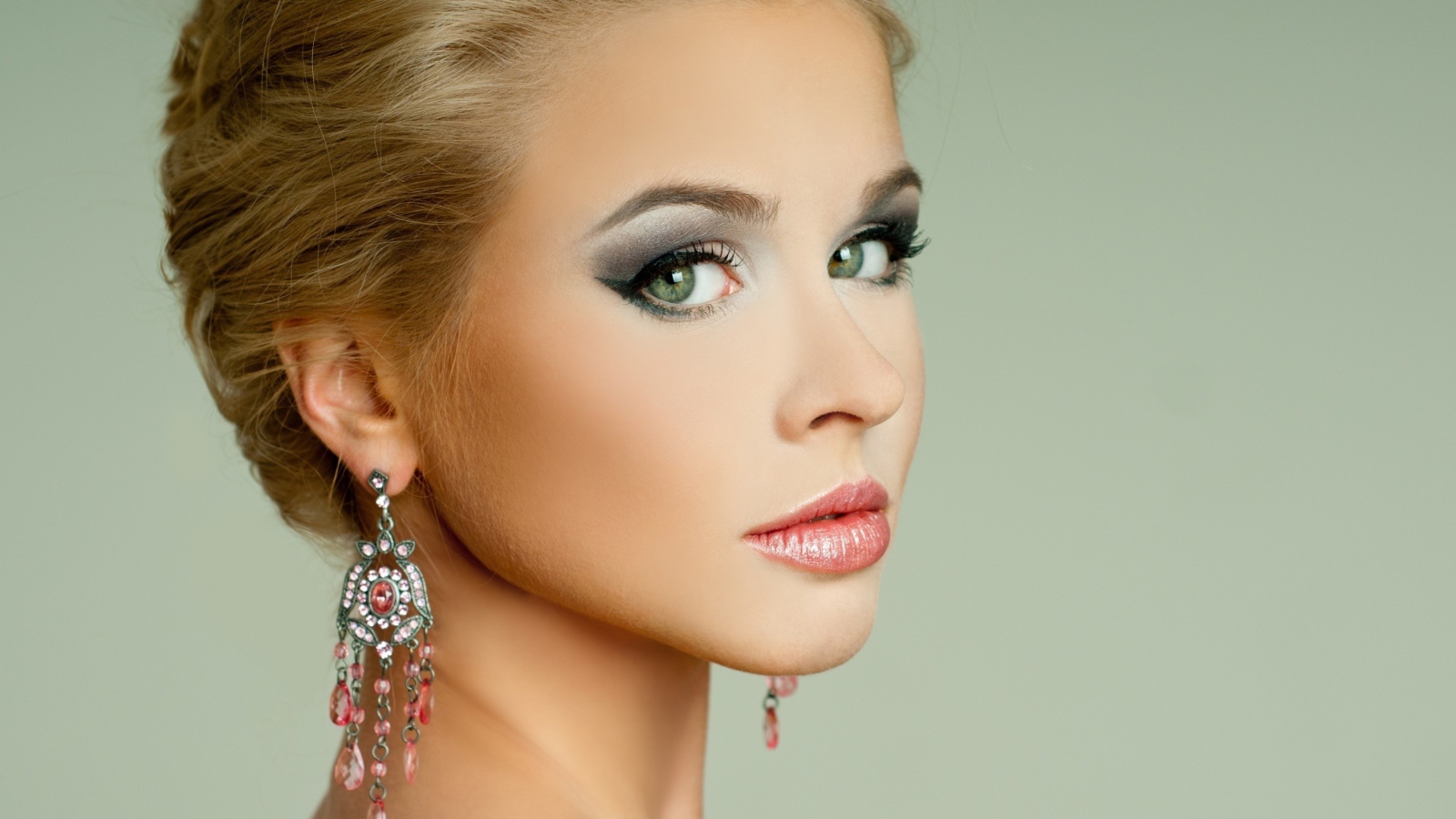 Красивая девушка блондинка с красивыми сережками на сером фоне