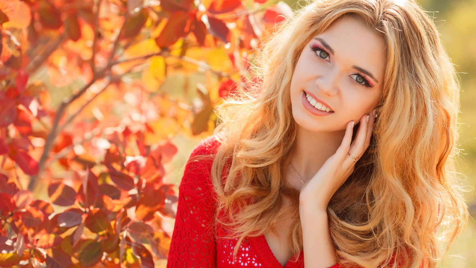 Красивая блондинка в красной кофте на улице осенью 