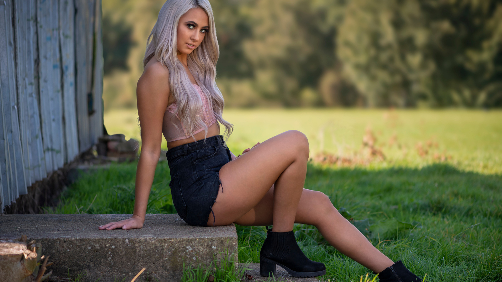 Красивая блондинка в черных шортах сидит на ступеньках 