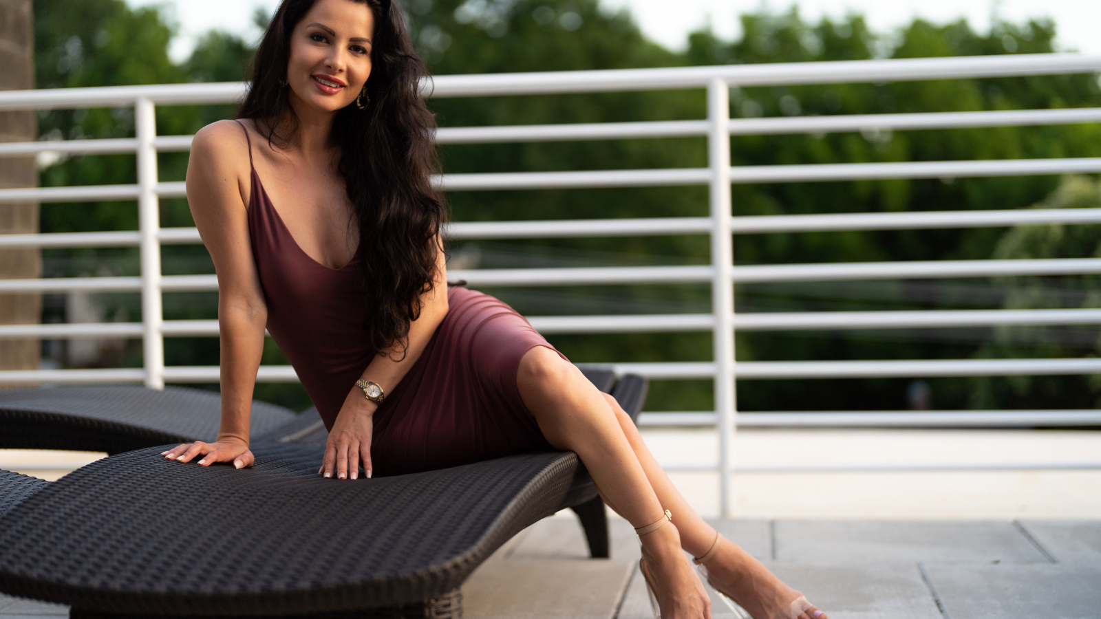 Красивая брюнетка в платье сидит на диване 