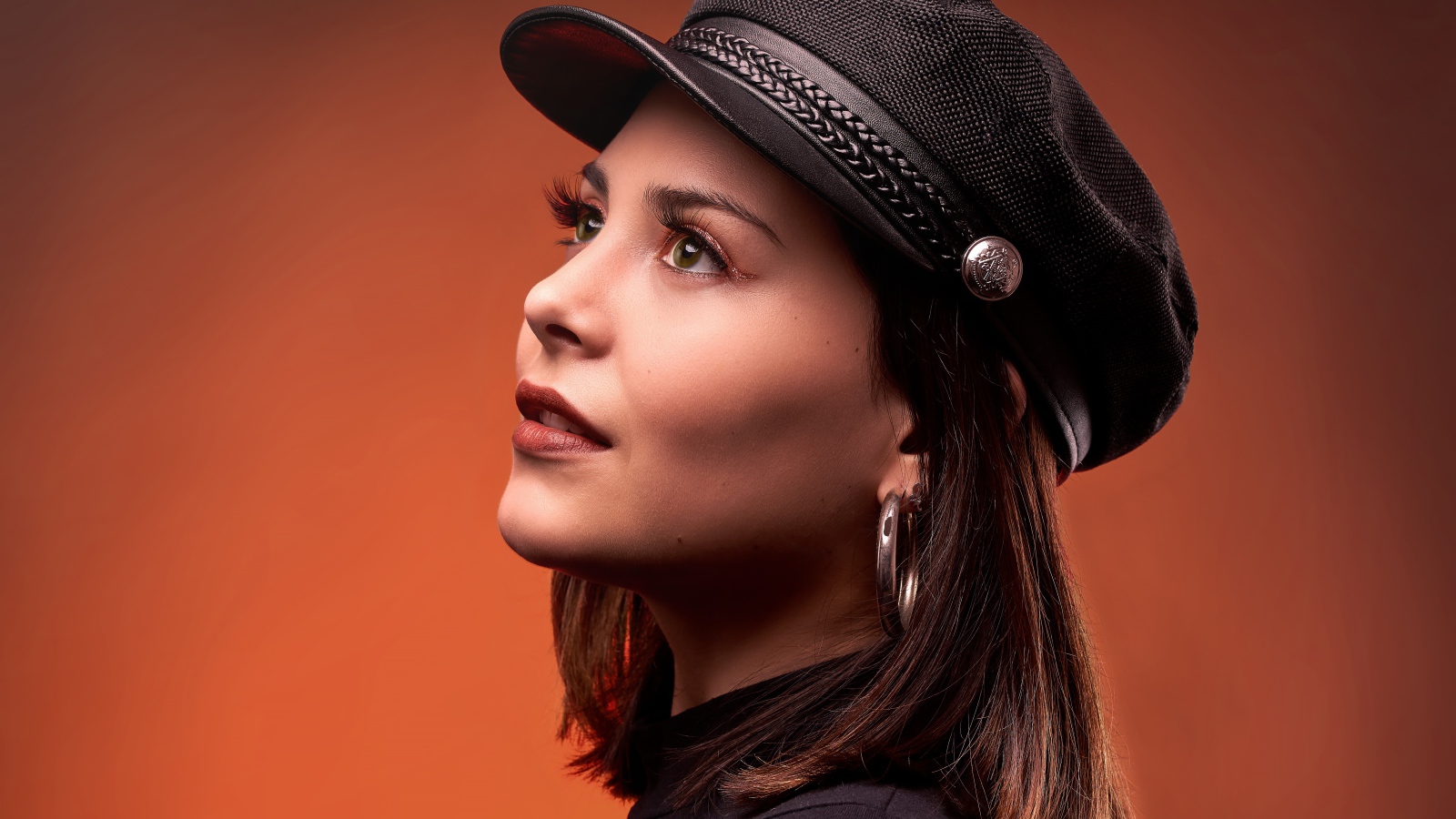 Красивая девушка в кепке на коричневом фоне