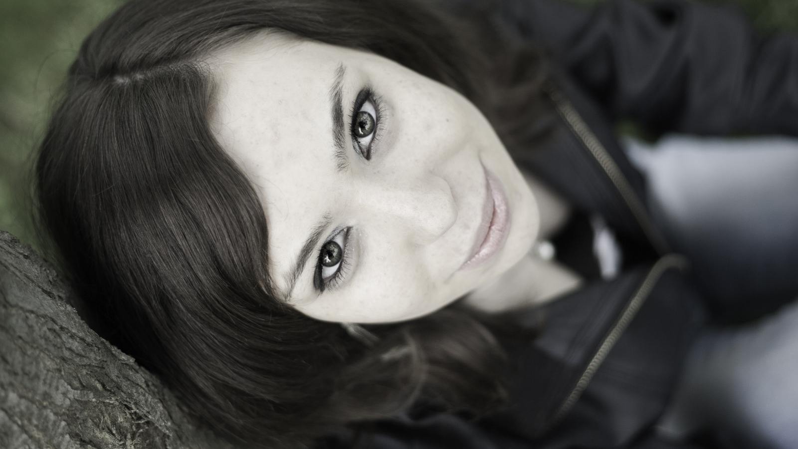 Красивая девушка смотрит вверх сидя под деревом  