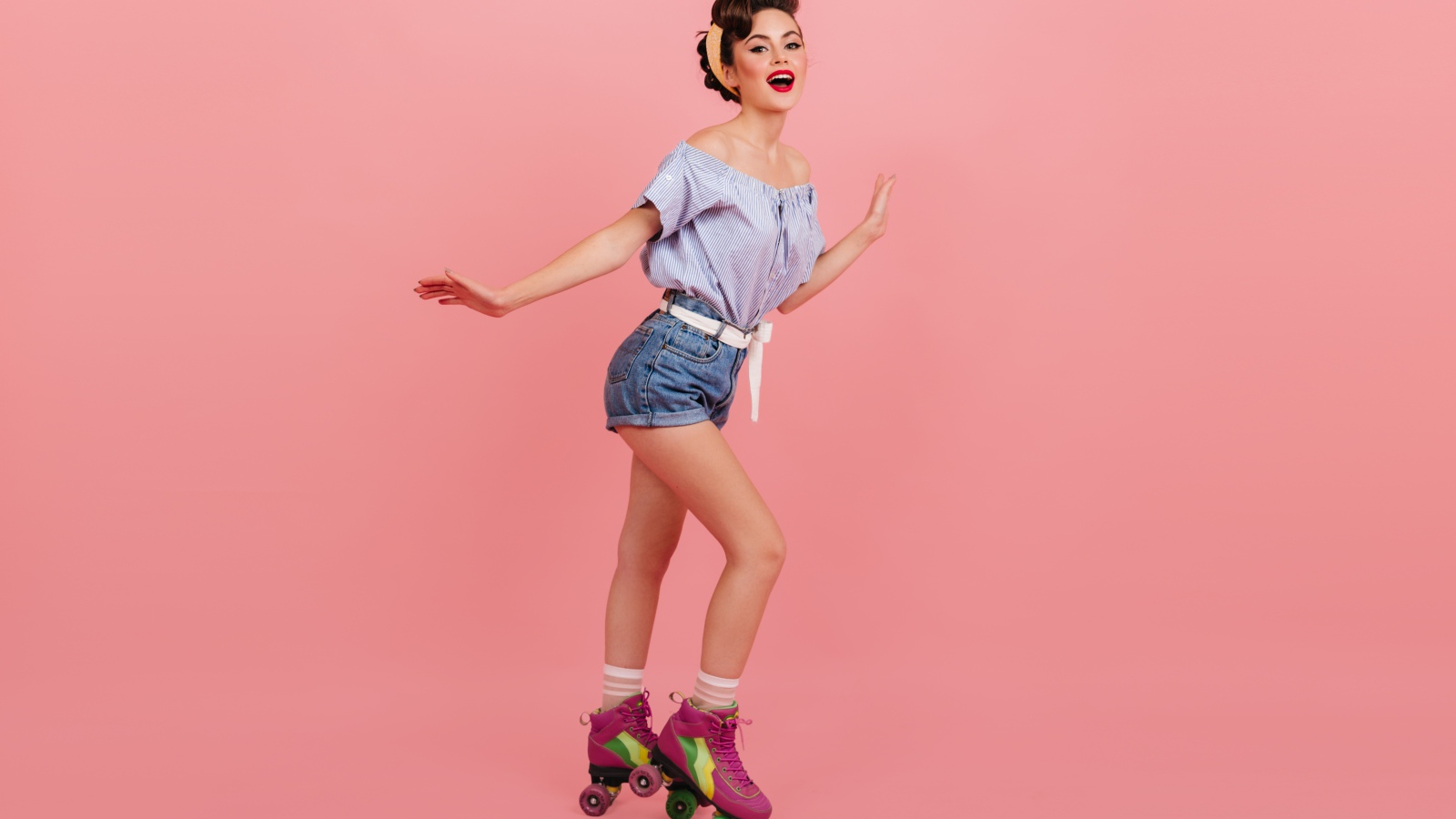 Красивая девушка на роликах на розовом фоне 
