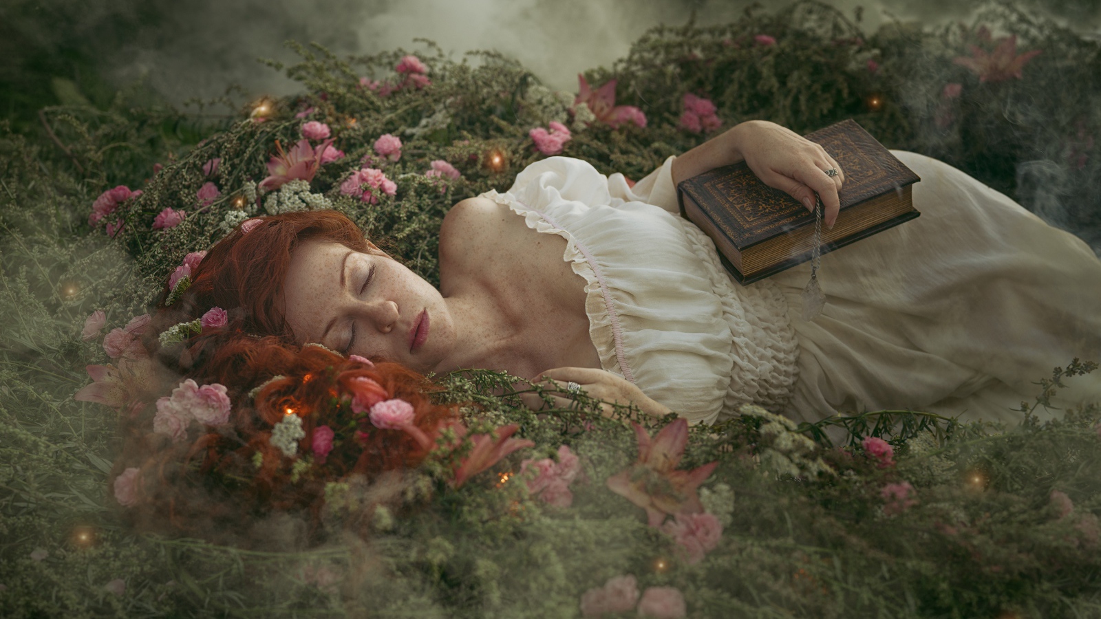 Красивая рыжеволосая девушка спит на земле с книгой