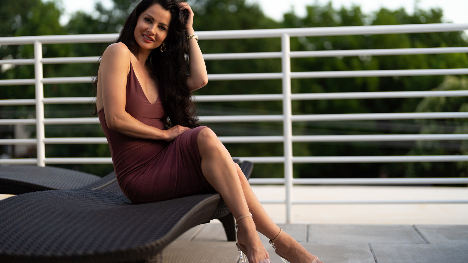 Красивая стильная брюнетка в платье сидит на диване