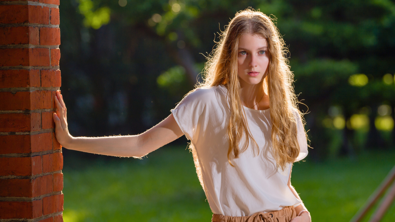 Красивая нежная девушка стоит у стены 