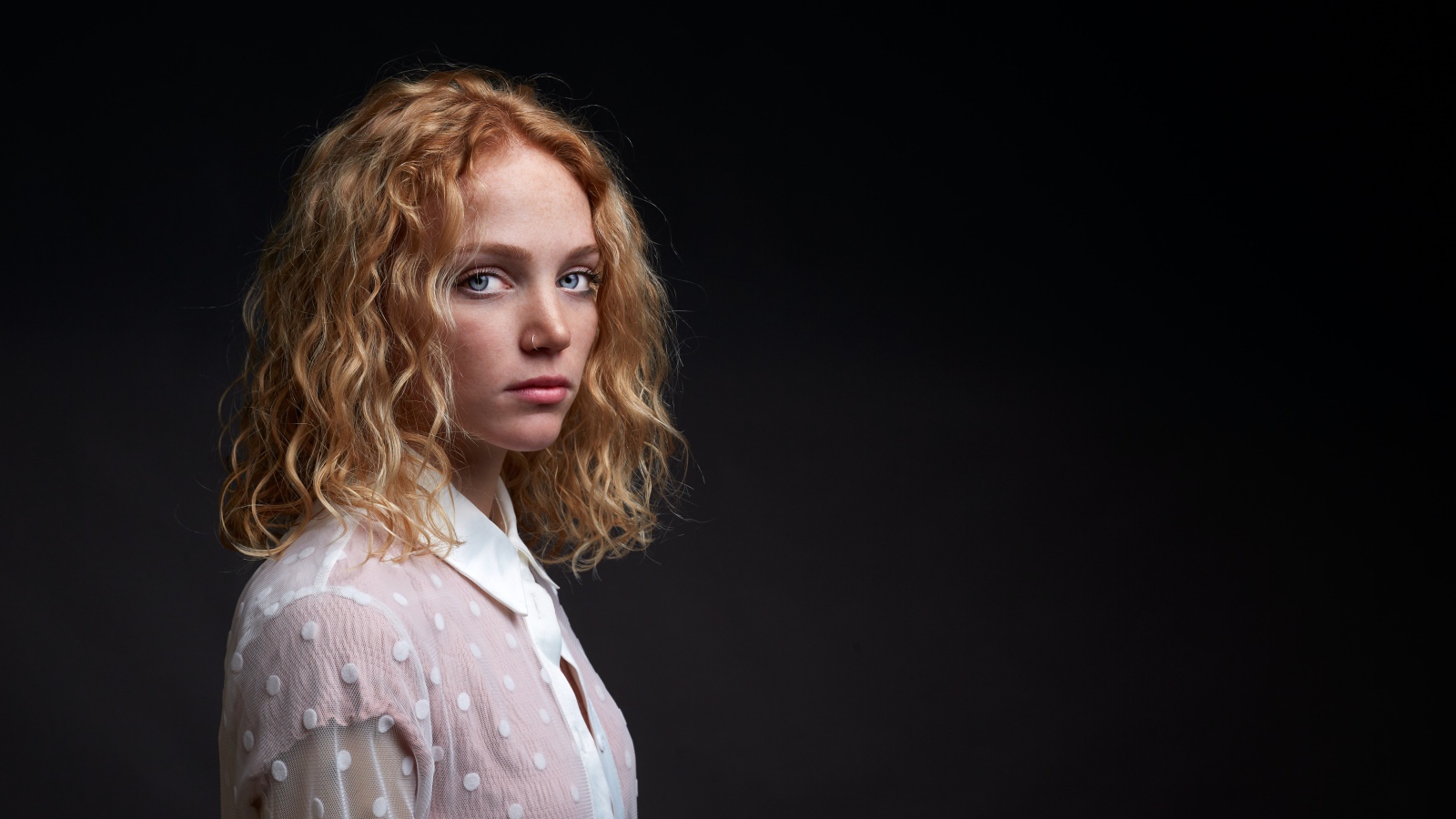 Голубоглазая девушка в белой рубашке на черном фоне
