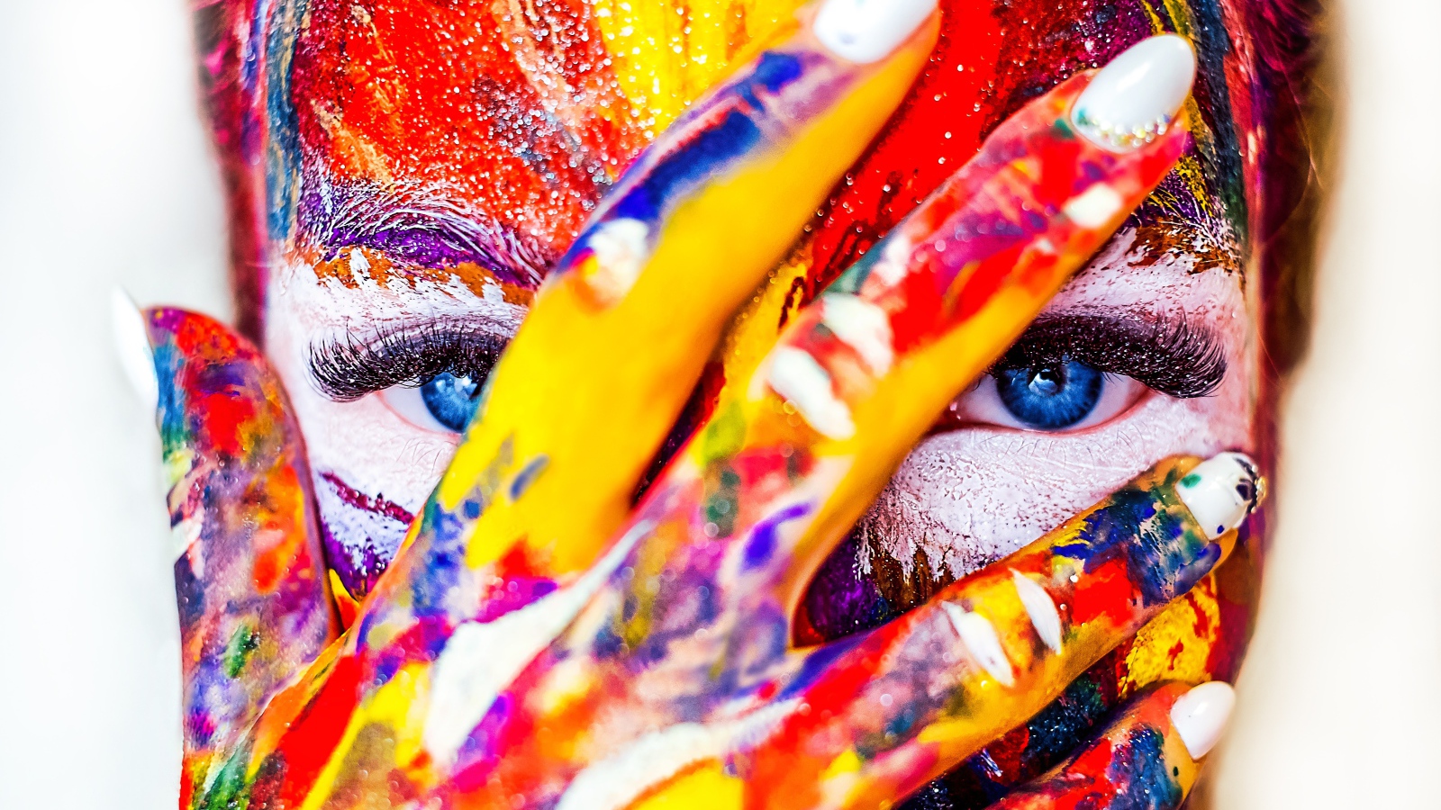 Голубоглазая девушка с лицом в краске на белом фоне