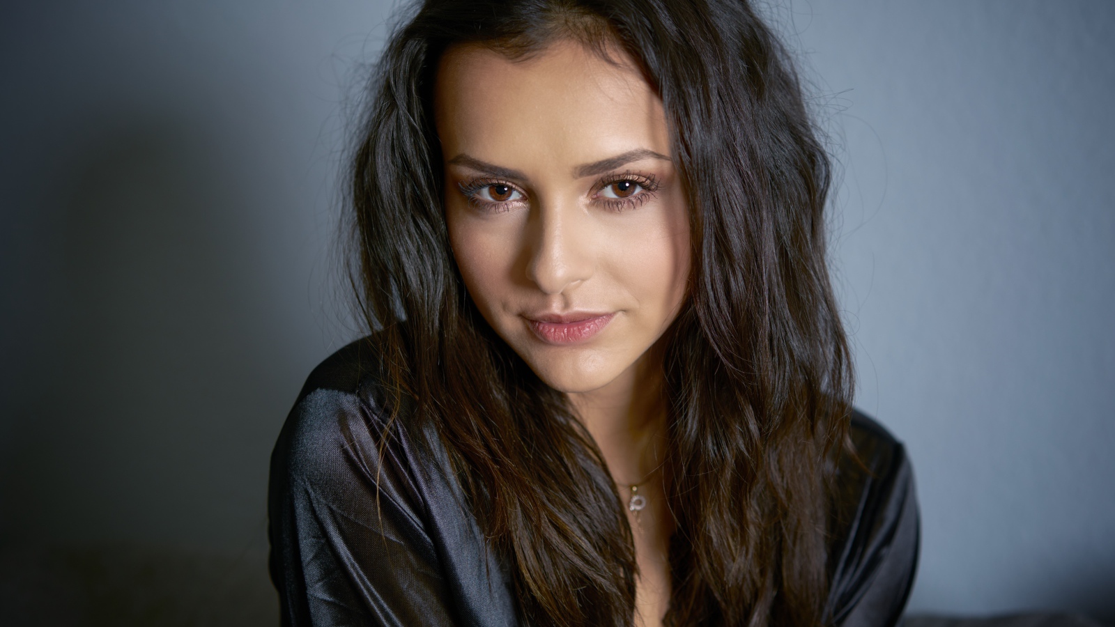 Кареглазая брюнетка в черном халате на сером фоне