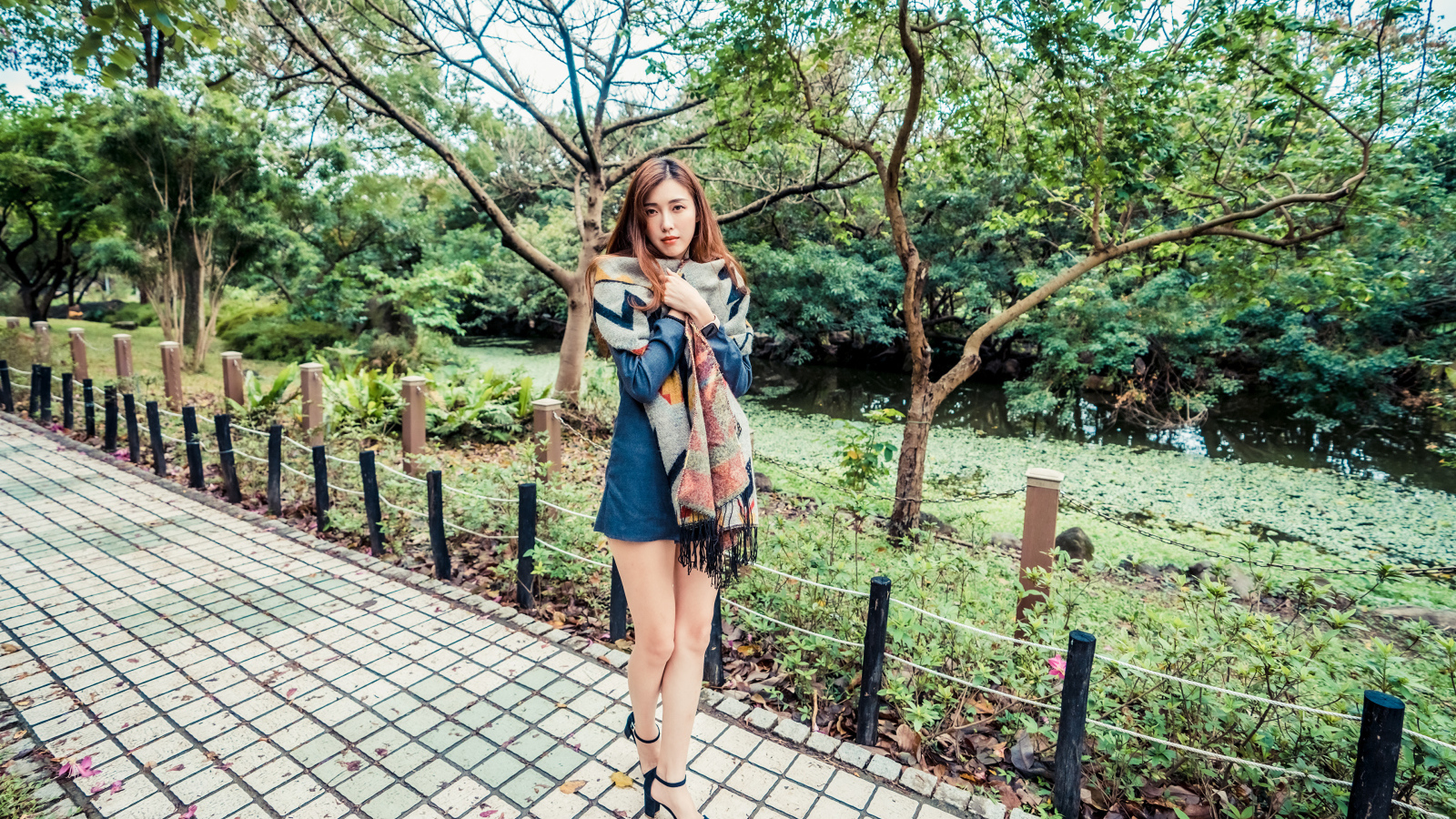 Милая девушка азиатка стоит в осеннем парке 