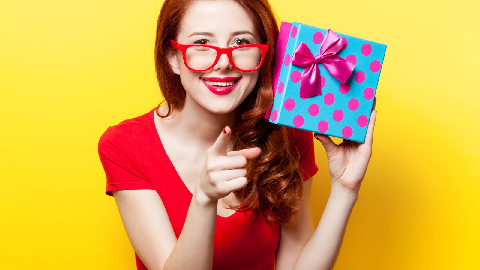 Девушка в очках с подарком в руке на желтом фоне