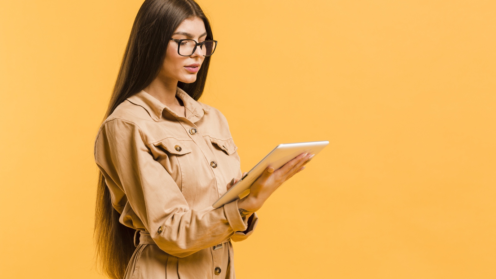 Девушка с планшетов руках на желтом фоне