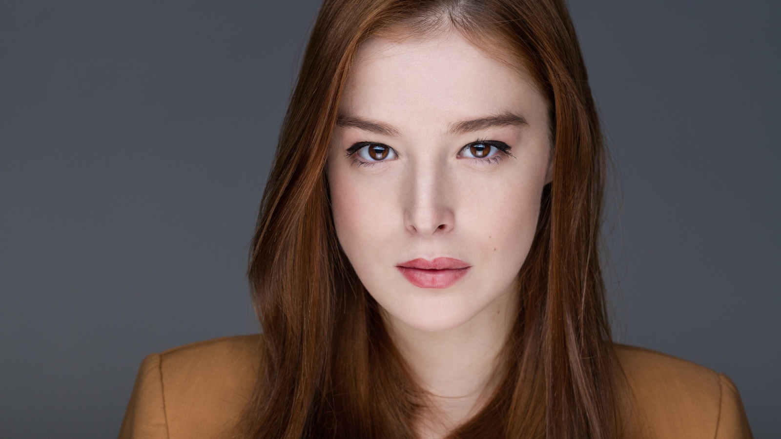 Рыжеволосая  молодая девушка на сером фоне