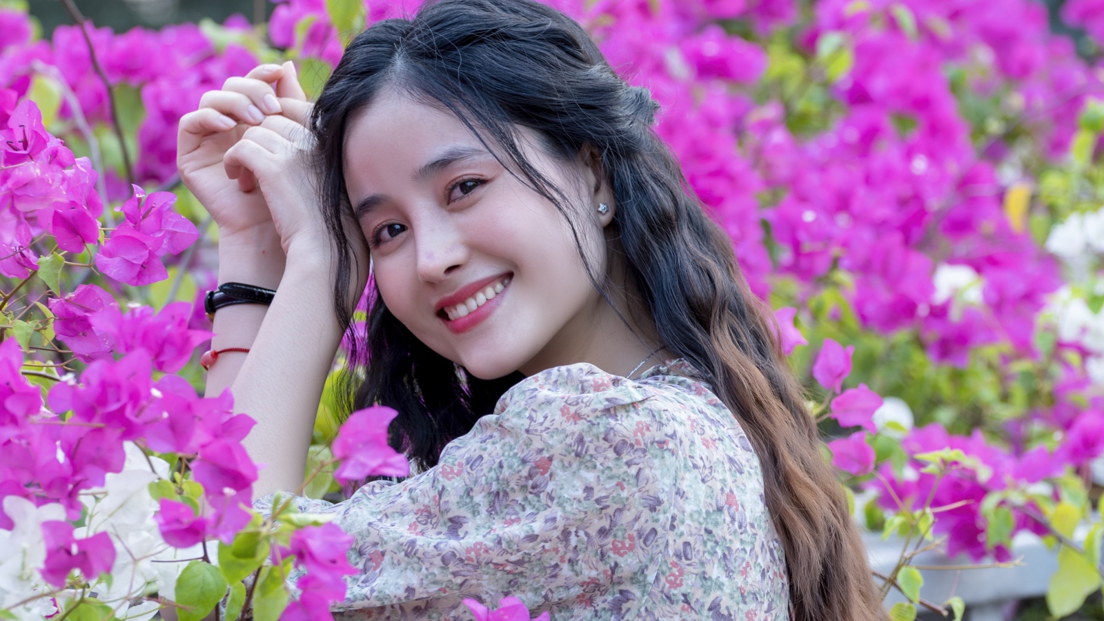 Улыбающаяся девушка азиатка на фоне розовых цветов