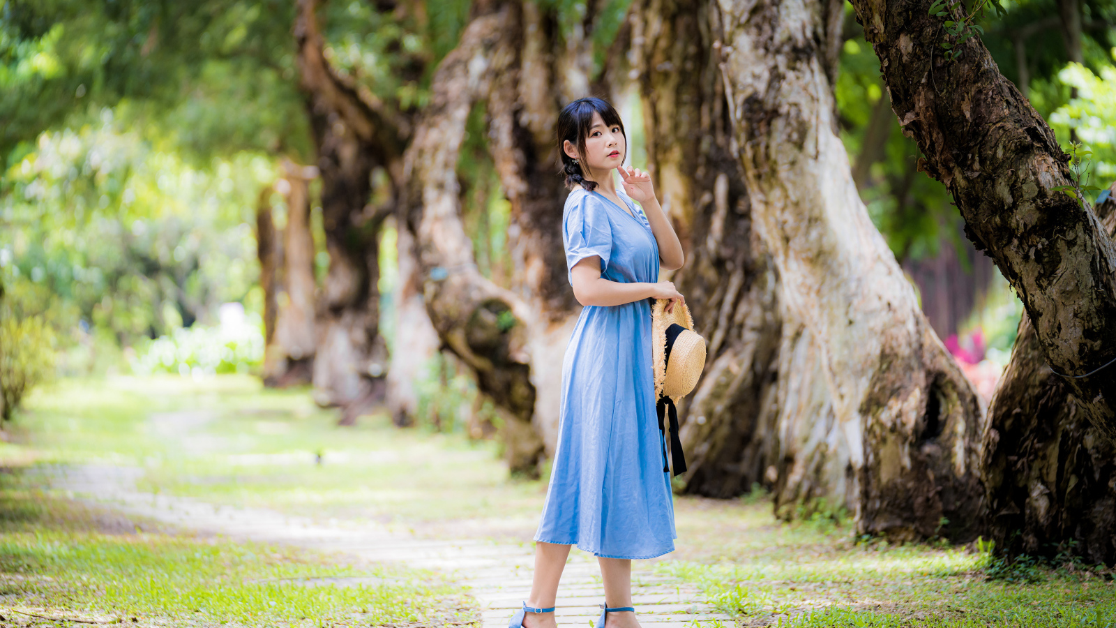 Стильная девушка азиатка в голубом платье в парке 