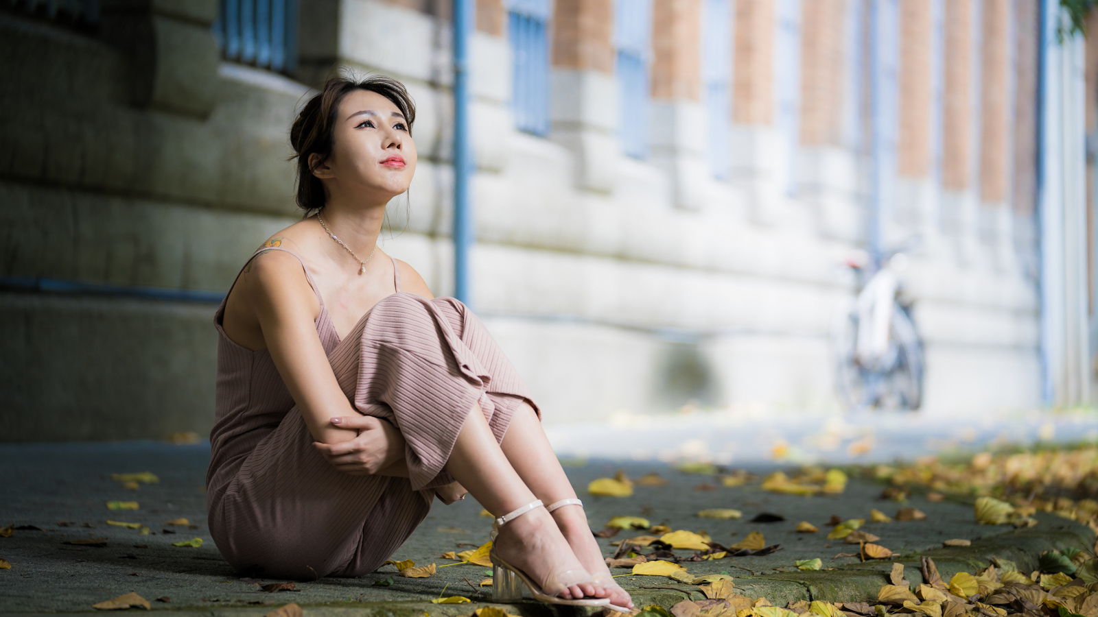 Молодая девушка азиатка сидит на земле с листьями 