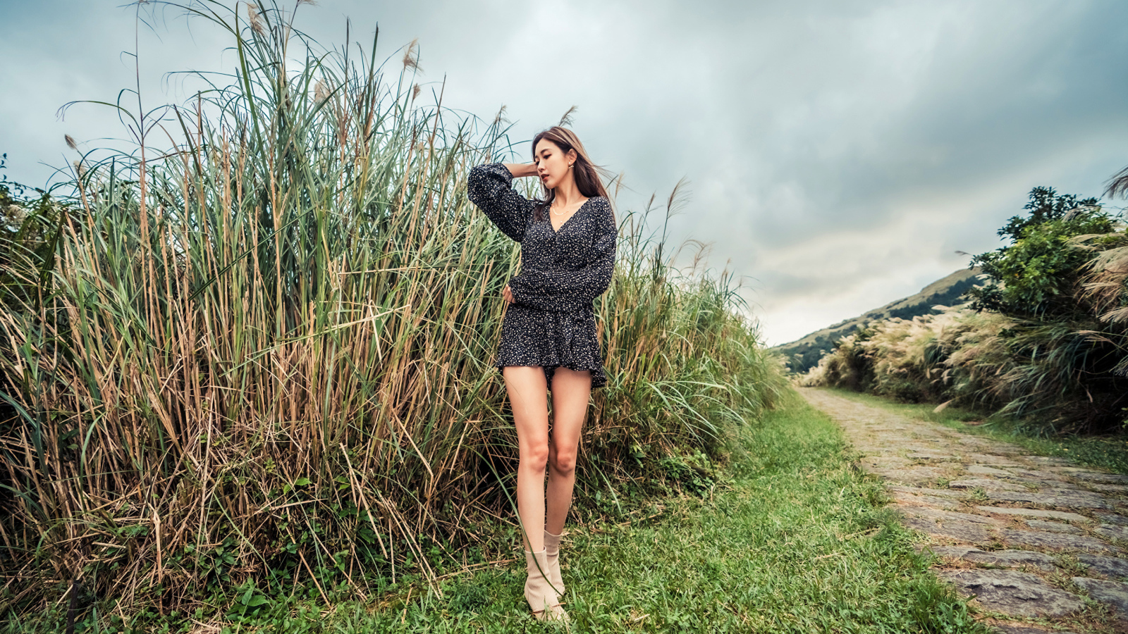 Молодая девушка азиатка стоит у зеленой травы