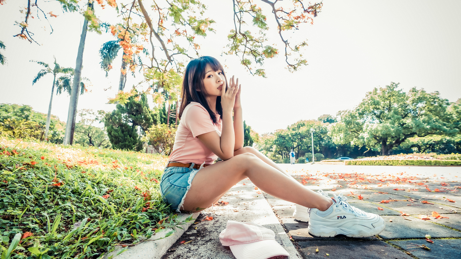 Молодая азиатка сидит на земле в осеннем парке