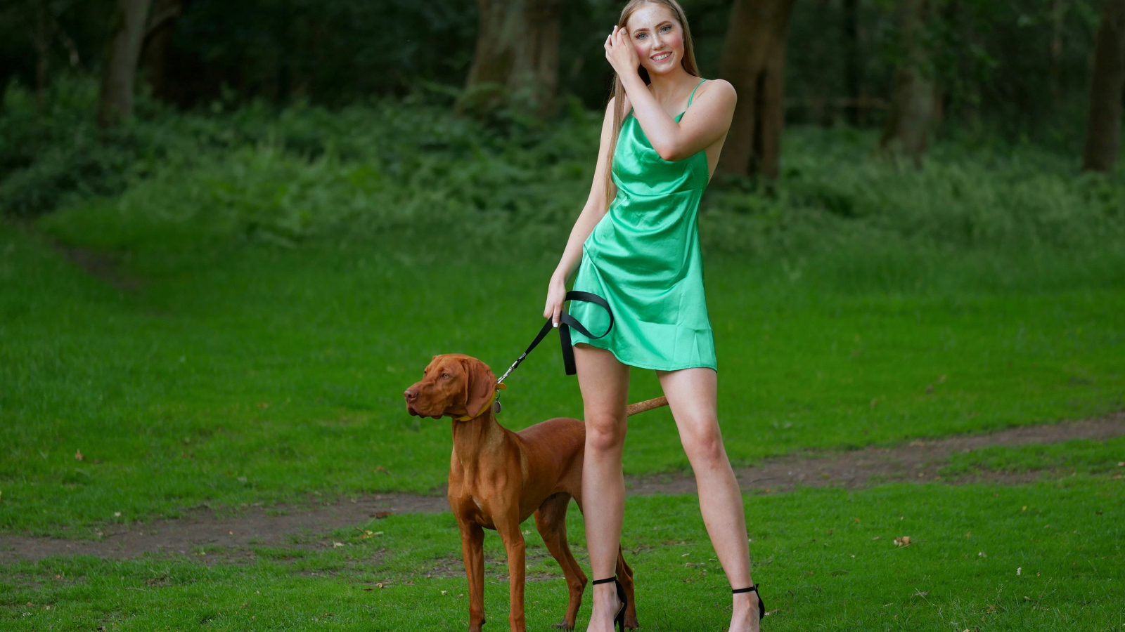 Молодая девушка гуляет с собакой в парке