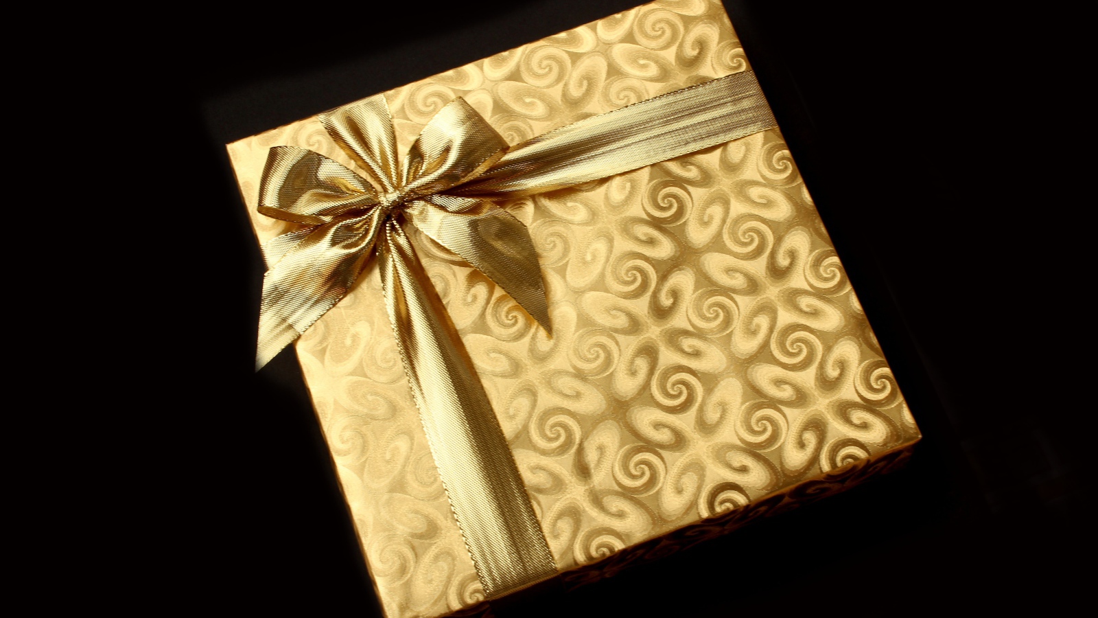 Золотая упаковка с подарком на черном фоне