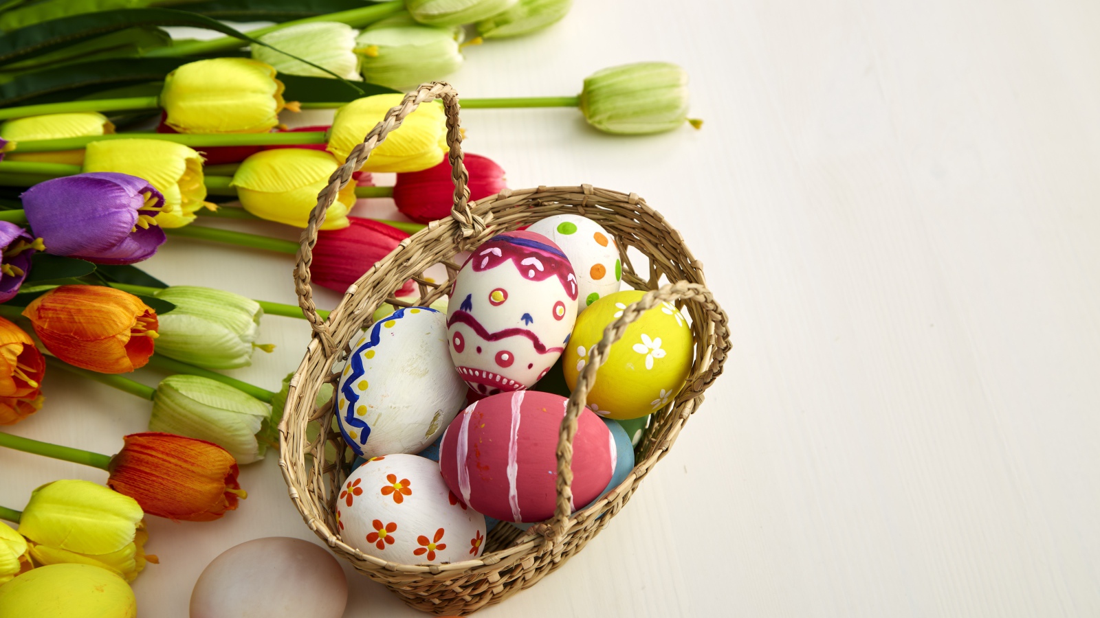 Корзина крашеных яиц с букетом тюльпанов