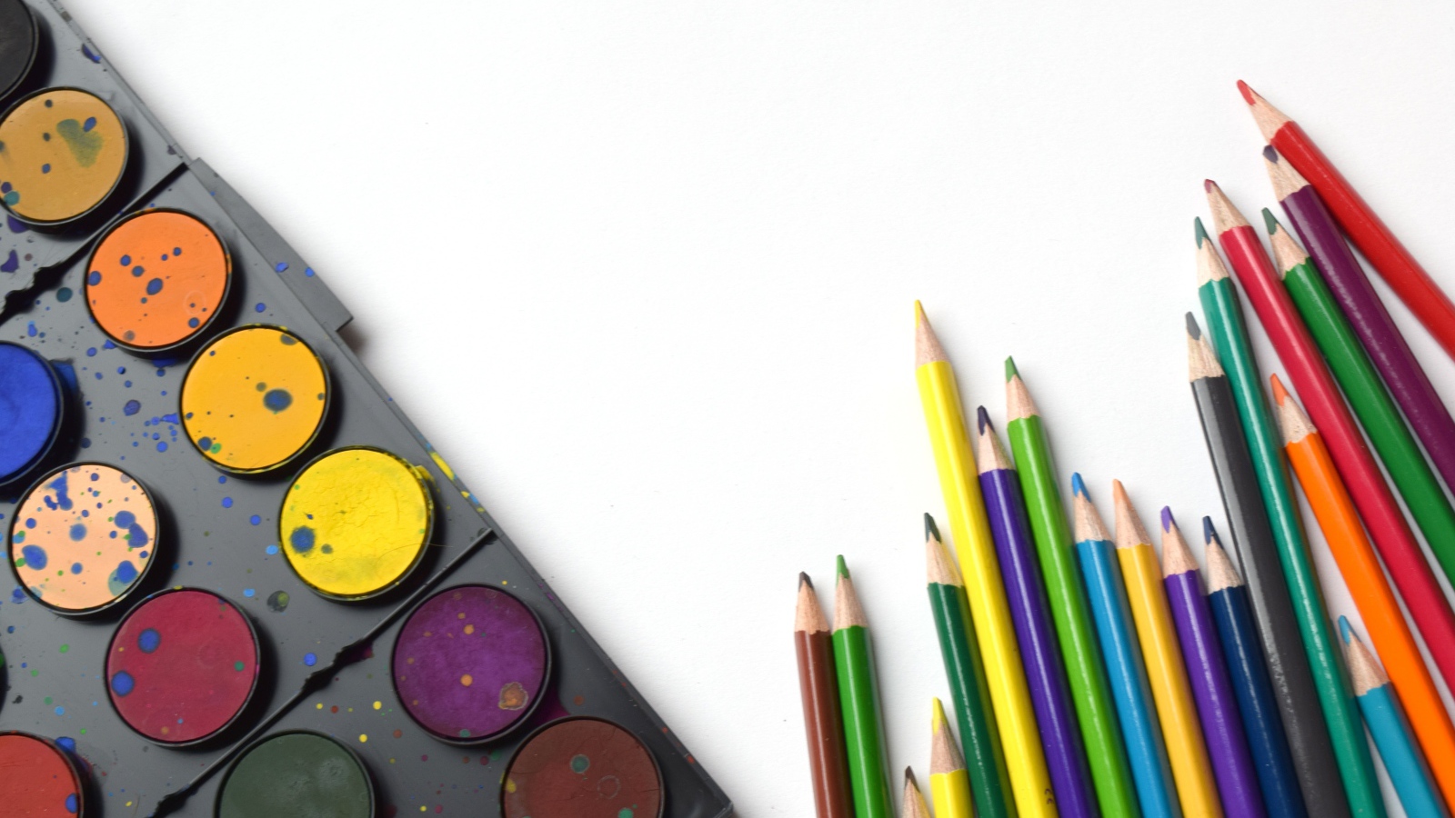 Разноцветные карандаши и краски на белом фоне