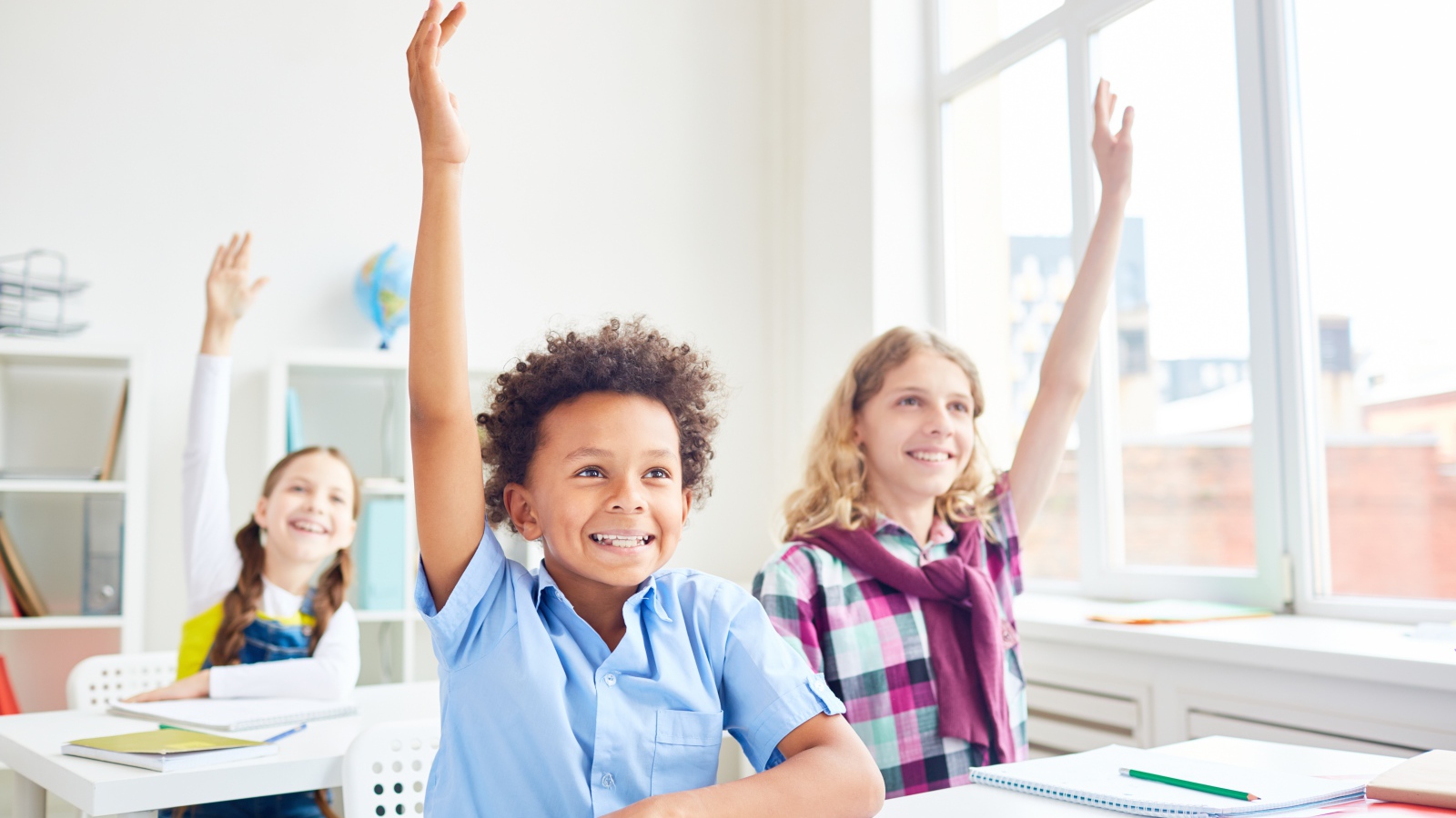 Дети школьники с поднятой  рукой в классе на 1 сентября 