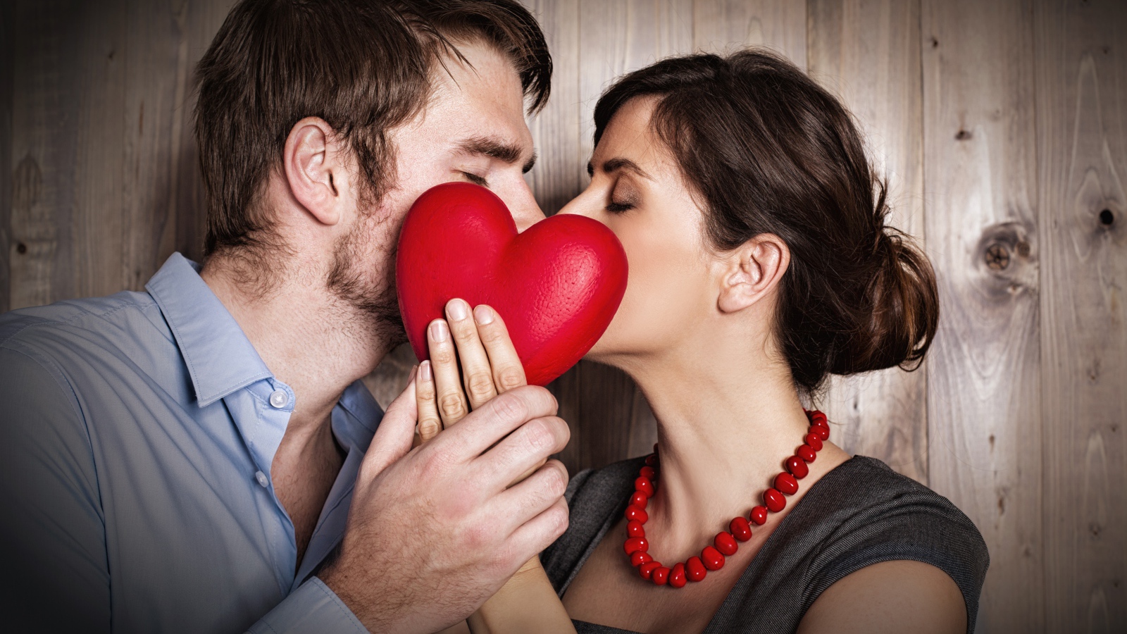 Поцелуй влюбленной пары за красным сердцем