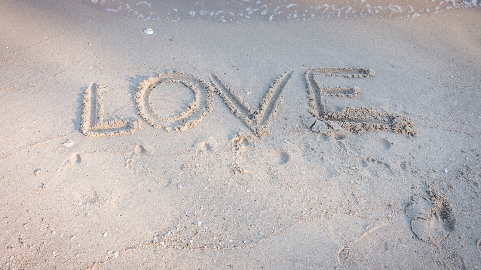 Надпись Любовь на мокром песке у моря