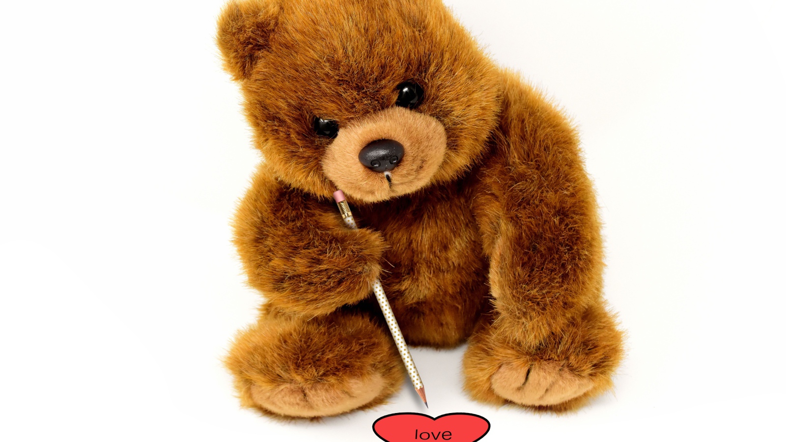 Игрушка медвежонок рисует сердце на белом фоне 
