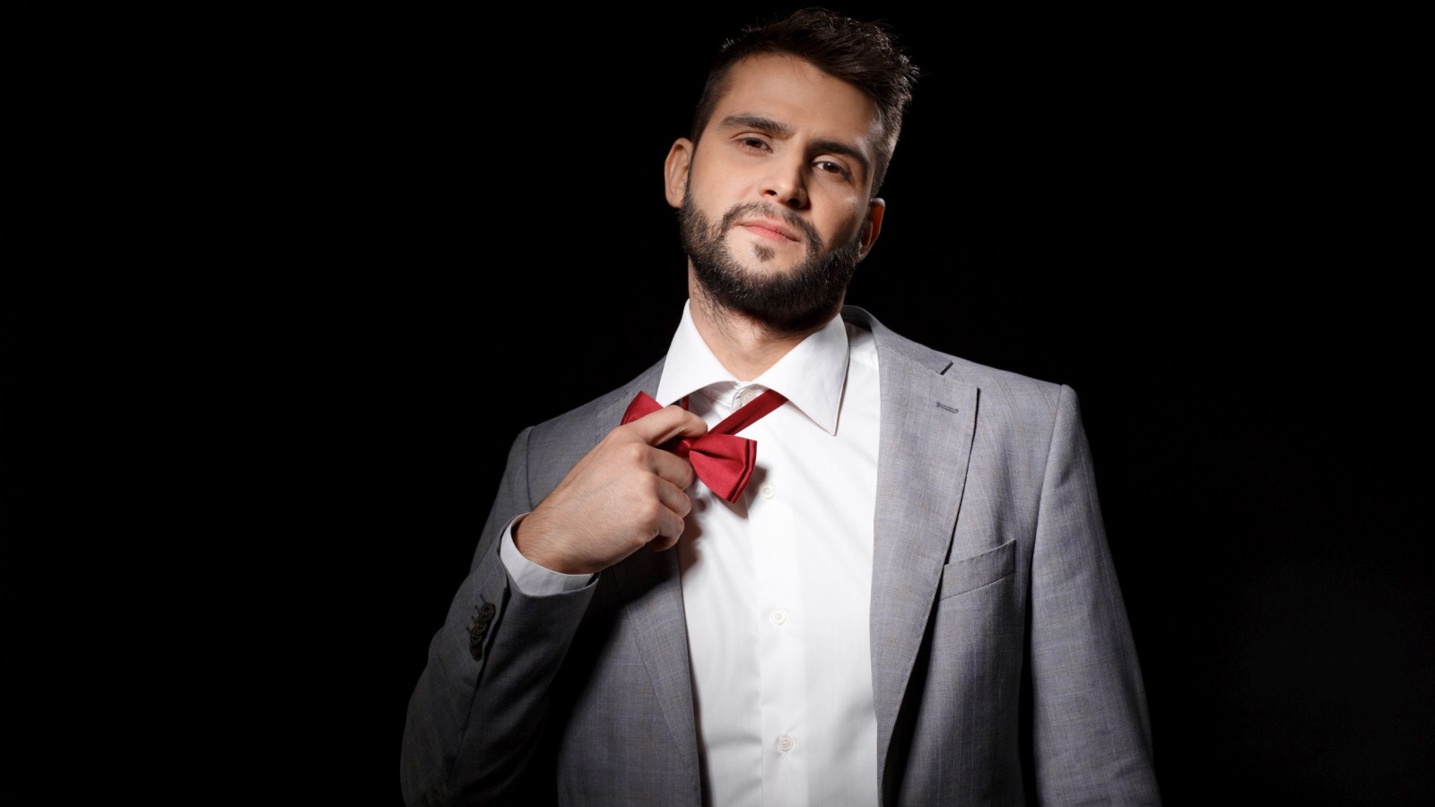 Красивый мужчина в сером пиджаке на черном фоне