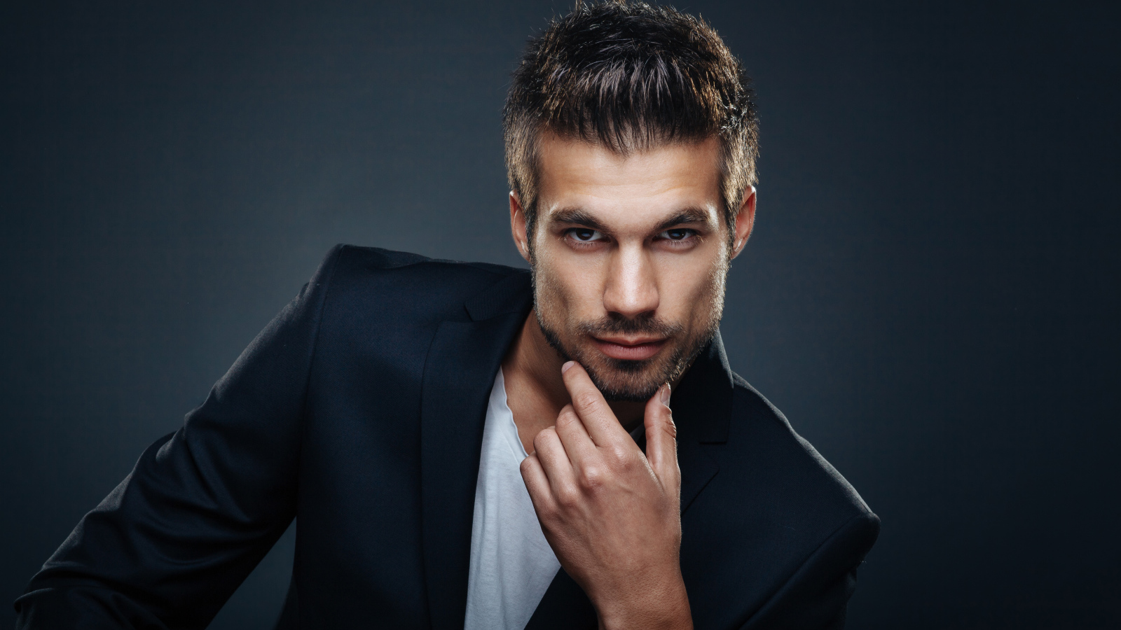 Красивый стильный мужчина в пиджаке на сером фоне 