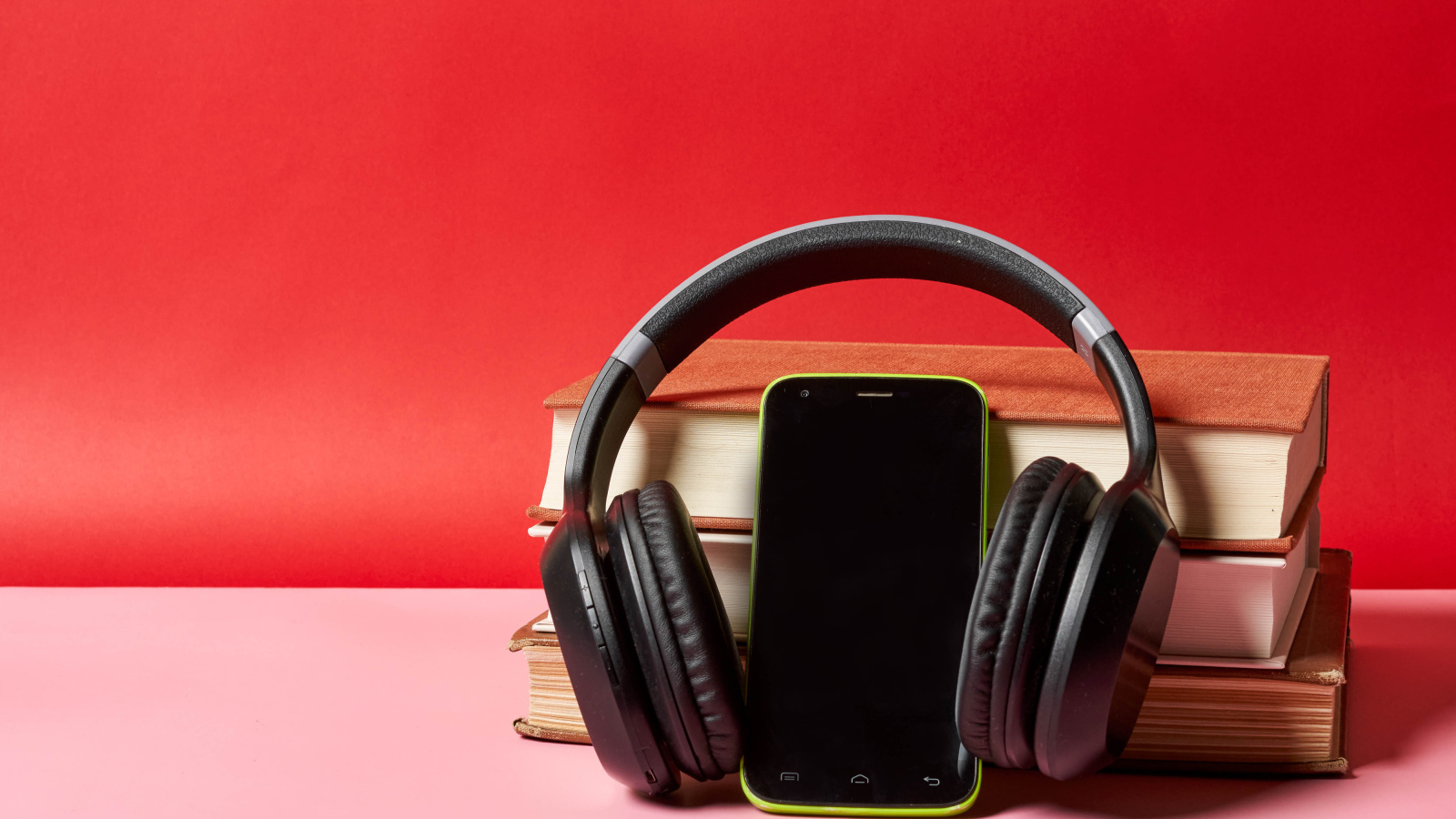 Смартфон, наушники и книги на красном фоне