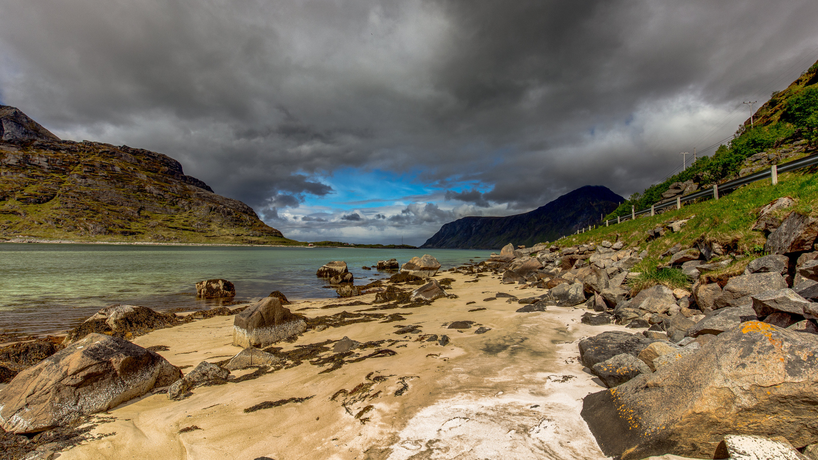 Большие камни на берегу фьорда под грозовым небом 