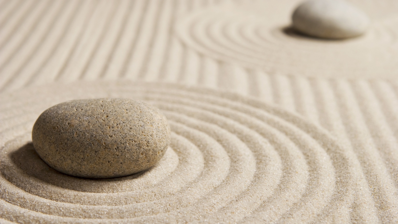 Большой серый камень на песке с кругами 