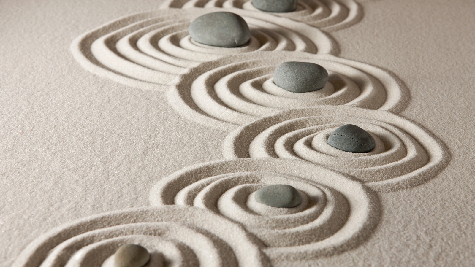 Маленькие серые камни с кругами на песке 