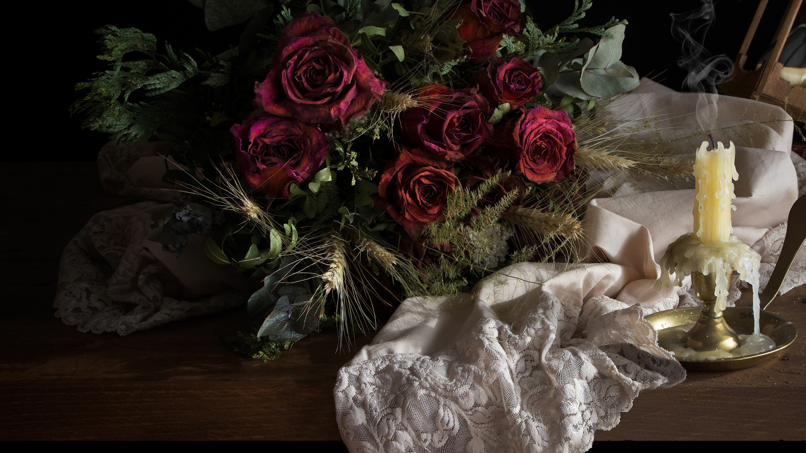 Завядший букет роз со свечой на столе