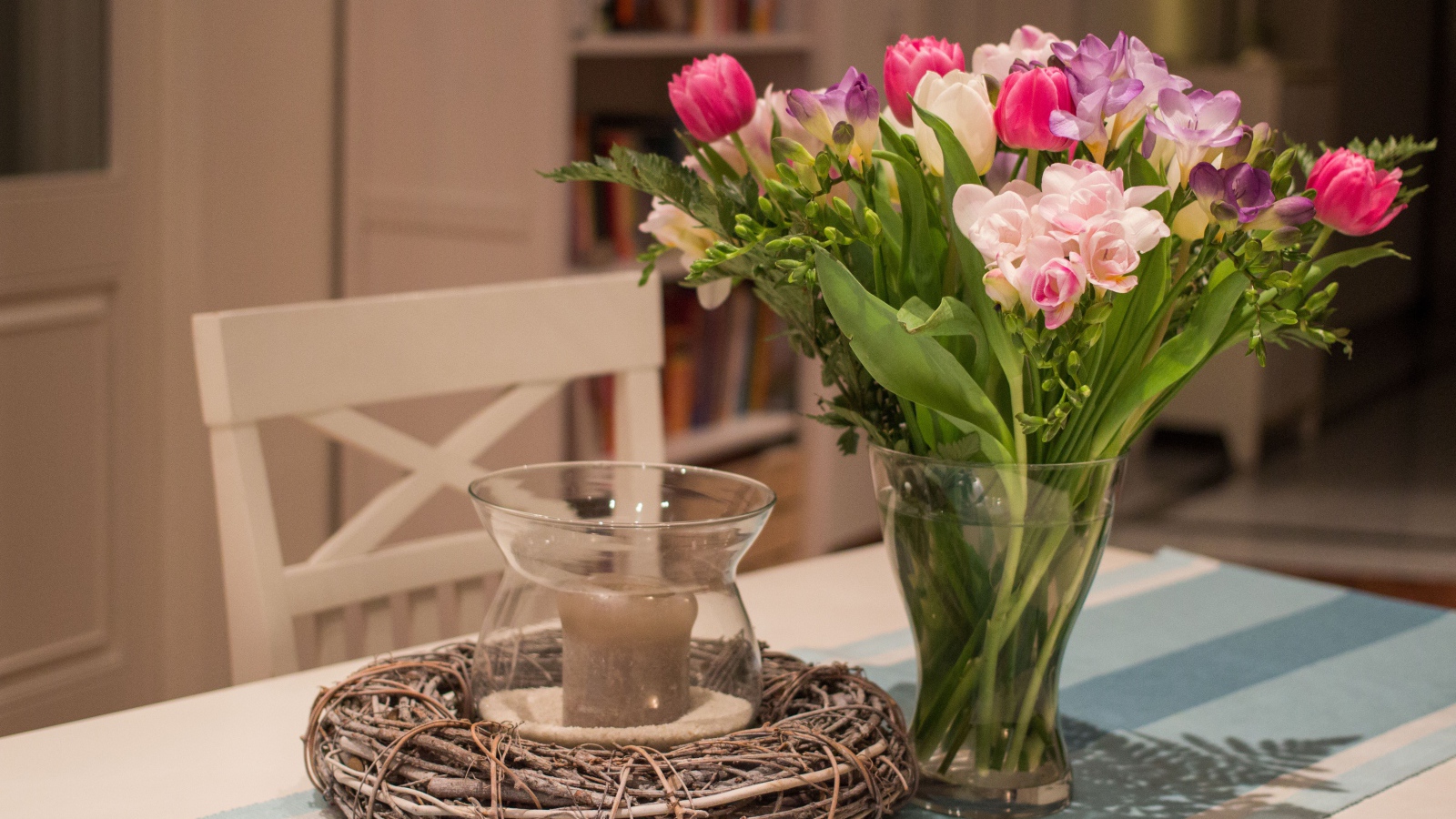 Красивый букет ярких цветов на столе со свечой