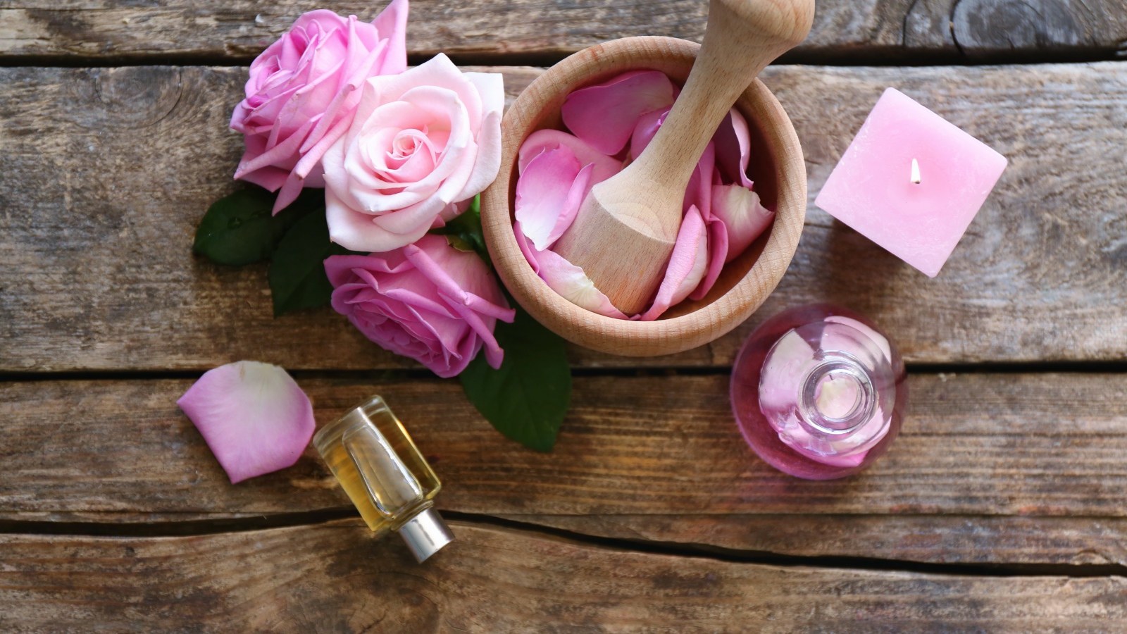 Лепестки розовой розы в ступке на столе с маслом