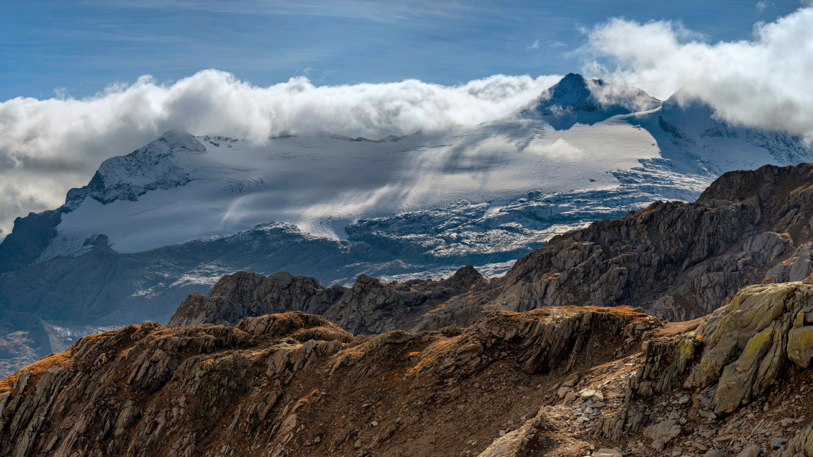 Густые белые облака над заснеженными Альпами
