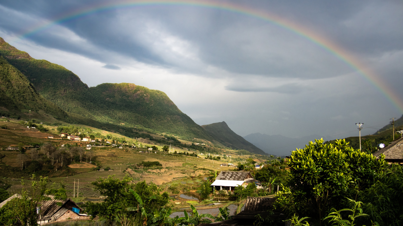 Большая разноцветная радуга в небе над горами
