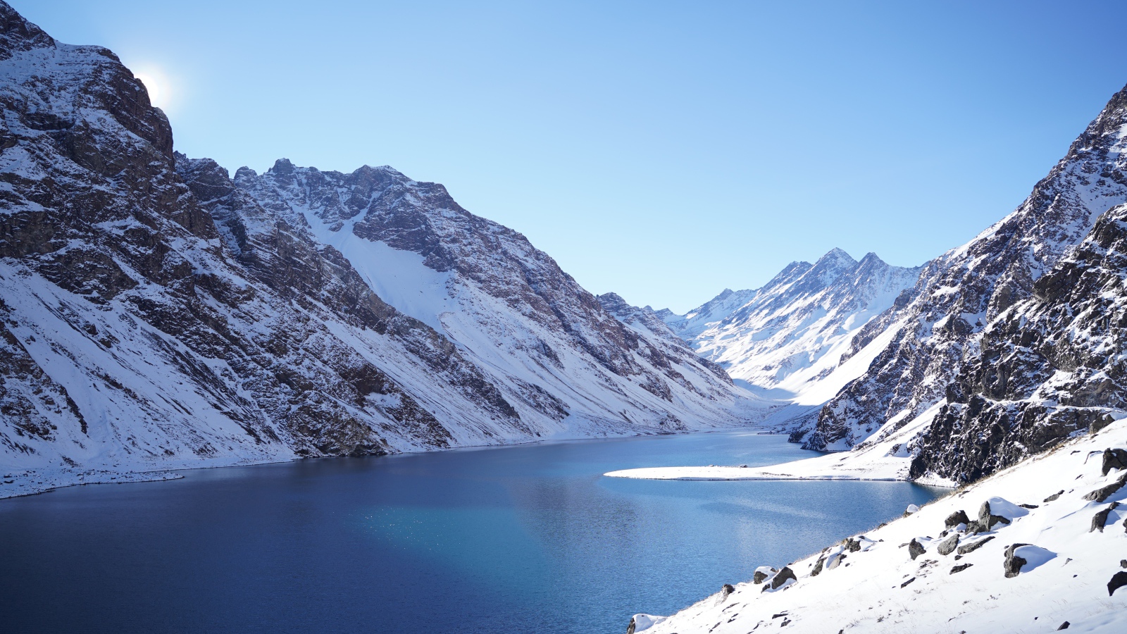 Озеро у покрытых снегом гор под голубым небом