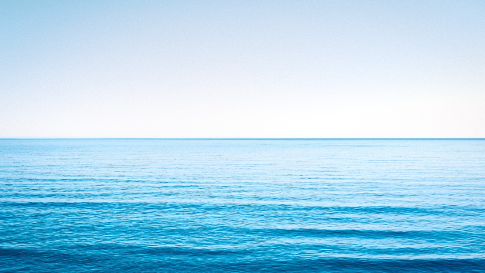 Спокойная голубая морская вода под голубым небом 