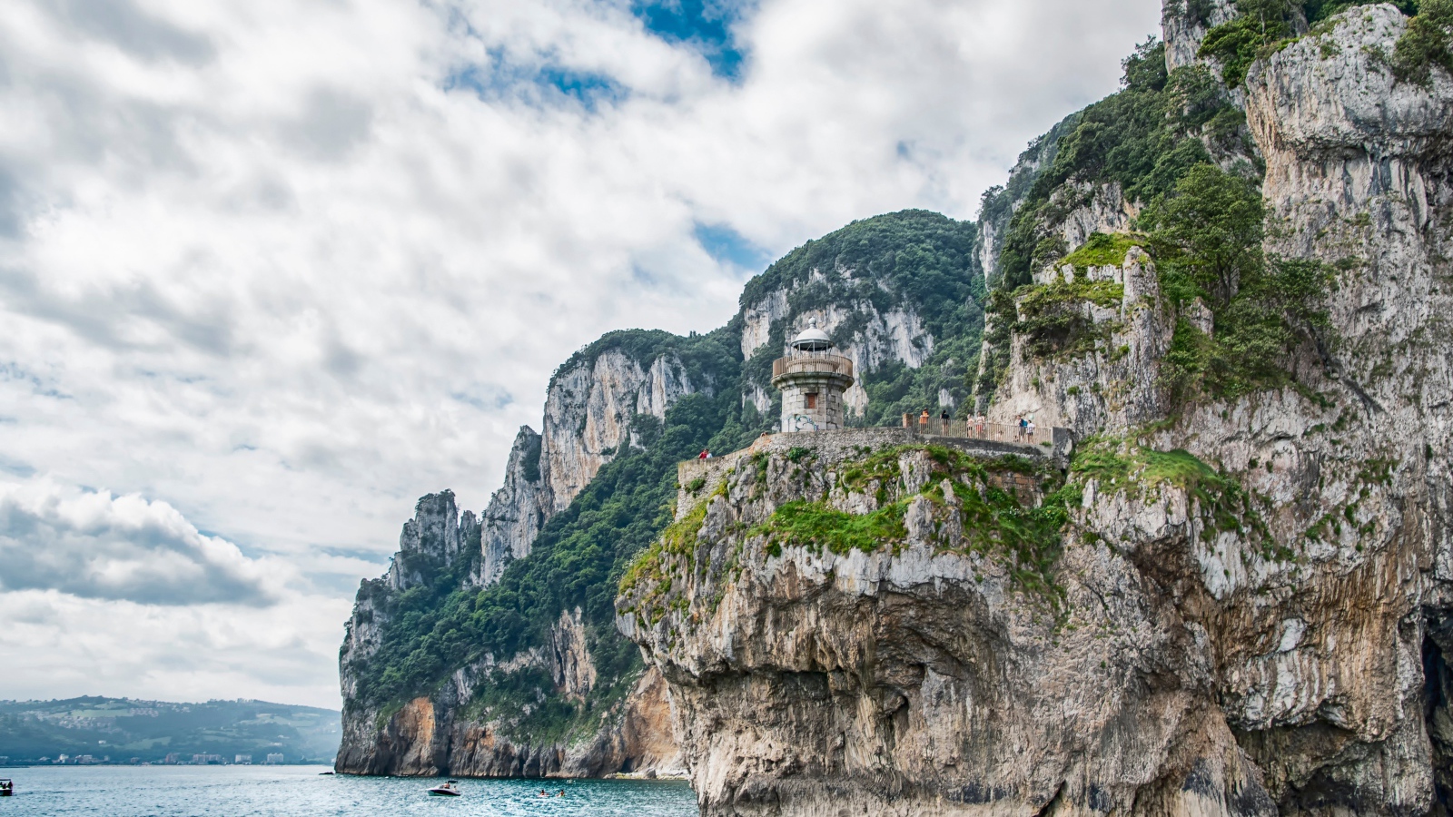 Высокие скалы у моря под белыми облаками 